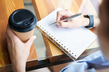 Close-up of unrecognizable woman sitting at table and drinking coffee