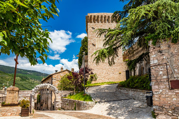 Wall Mural - The tower and the medieval walls, in stone and brick, with merlon. A Roman stone arch. In Spello, province of Perugia, Umbria, Italy.