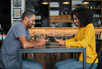 Wall Mural - Couple at cafe table using mobile phones