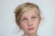 © Cat - Portrait of a young blond blue eyed girl looking up thinking against a white background