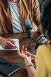 © LIGHTFIELD STUDIOS - cropped view of radio host writing in notebook while interviewing woman in broadcasting studio