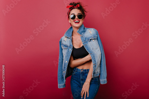 Fotografía Pleased girl wears jeans laughing on claret background