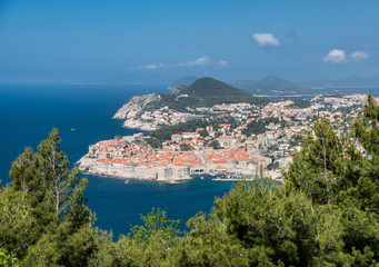 Trees frame an aerial shot of the old town of Dubrovnik and the city walls in Croatia