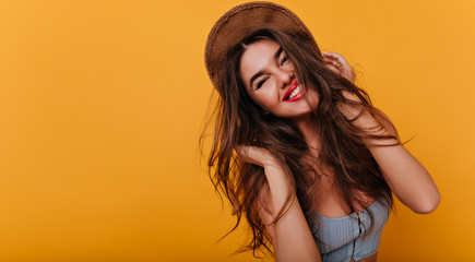 Carefree white woman with trendy hairstyle laughing after photoshoot in summer outfit. Close-up portrait of enchanting girl in hat smiling to camera.