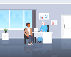 Wall Mural - patient receiving a prescription african american man having consultation with senior doctor sitting at workplace medicine and healthcare concept modern hospital medical office full length flat