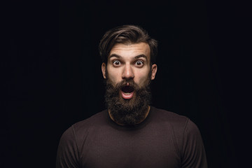 Close up portrait of young man isolated on black studio background. Photoshot of real emotions of male model. Wondering, exciting and astonished. Facial expression, human emotions concept.