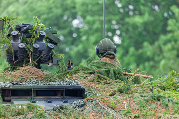 German soldier sits on a military fully camouflaged vehicle