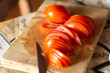 Preparing healthy food. Sliced ​​red tomato on the kitchen table in the home kitchen