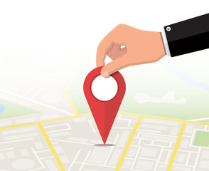 Poster - Location pin in hand and map. City map with houses, parks, streets and roads. City aerial view. GPS, navigation and cartography. Vector illustration in flat style