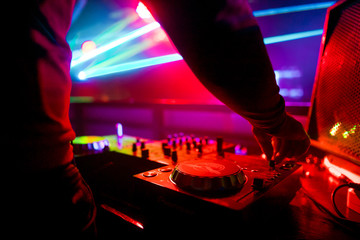 Dj mixing outdoor at beach party festival with crowd of people in background - Summer nightlife view of disco club outside - Soft focus on hand - Fun ,youth,entertainment and fest concept