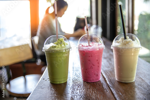 Many types of milk shake in plastic cup with plastic straw put on wood  table , soft sunlight through branch to table in coffee shop. - Stock Image  - Everypixel