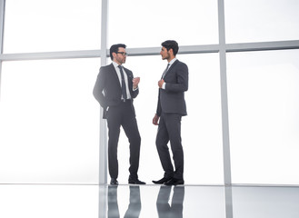 two businessmen standing near a large office window