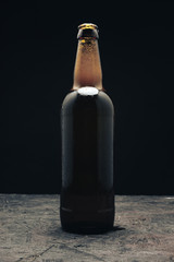 Aufkleber - Glass brown Bottle of beer on a dark wooden table and black background behaid.