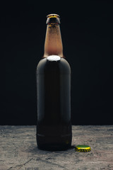 Aufkleber - Glass brown Bottle of beer on a dark wooden table and black background behaid.