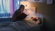 © Gorodenkoff - Young Loving Mother Reads Bedtime Stories to Her Little Beautiful Daughter who Goes to Sleep in Her Bed.