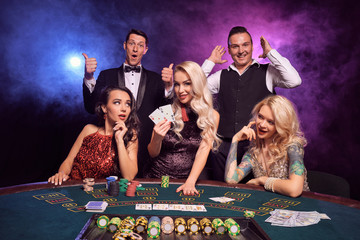 Group of a young wealthy friends are playing poker at a casino.