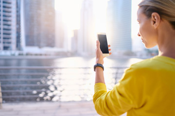 Young woman using smartphoneon the city embankment.