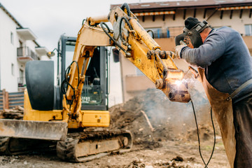 Wall Mural - construction and building site, broken excavator and professional welder