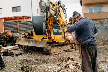 Wall Mural - Mechanic fixing excavator on construction site