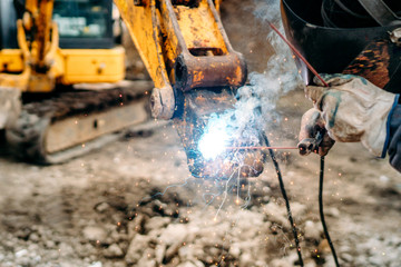 Wall Mural - close up of welding details, sparks on construction site excavator