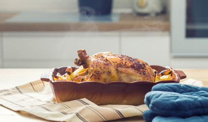 Wall Mural - Roasted whole chicken with potatoes in baking dish. Tasty food at home on the kitchen counter