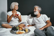 © luengo_ua - Good morning! Senior family couple enjoying breakfast in bed.