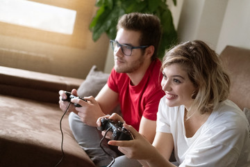 Young couple plays a video game with the console on the couch at home