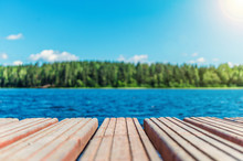Wooden Timber Of A Rural Mooring On A Lake In The Middle Of The Forest. A Peaceful River Dock In The Woods.Sunny Footbridge. Minimal Background With Blue Sky,clean Lake And Mooring In The Country Side