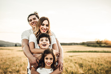 Portrait of a happy young family smiling in the countryside. Concept of family fun in nature.