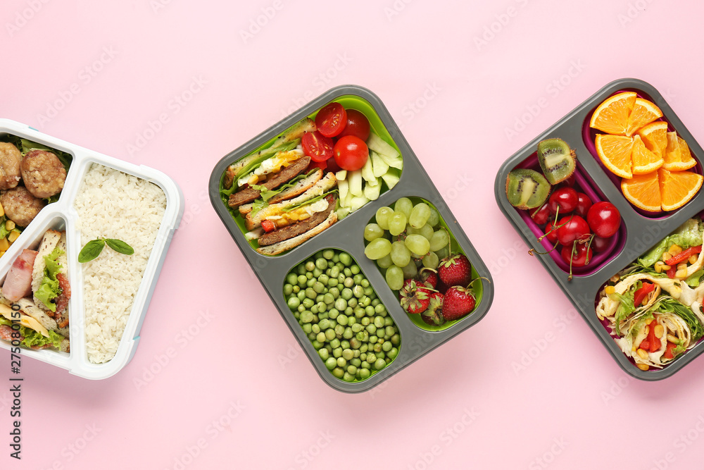 School lunch boxes with tasty food on color background