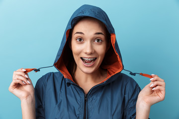 Wall Mural - Portrait of a cheerful young girl wearing raincoat standing