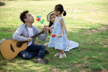 Wall Mural - Happy Asian family. Father, mother and daughter in a park at natural sunlight background. Family vacation concept.