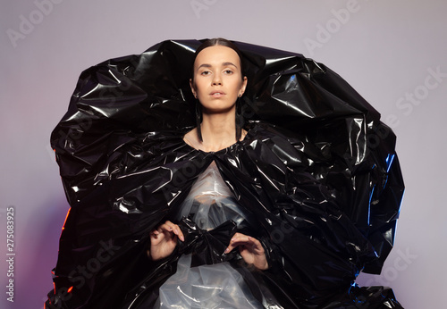 Fotomural Girl posing in a dress made of plastic film. Fashion portrait.