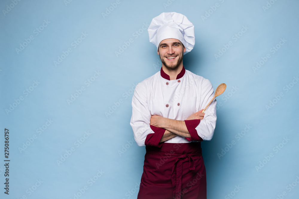 Portrait of positive toothy chef cook in beret, white outfit having tools in crossed arms looking at camera. - obrazy, fototapety, plakaty 