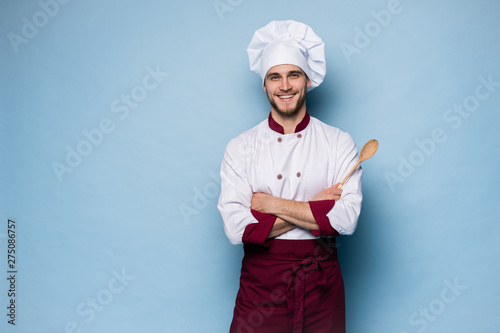 Fotomural Portrait of positive toothy chef cook in beret, white outfit having tools in crossed arms looking at camera