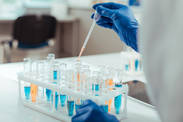 Wall Mural - close up of a scientist hand above test tubes