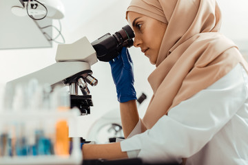 Smart intelligent woman studying samples through microscope