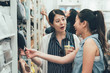 © PR Image Factory - Two smiling female friends selecting products in grocery store. young girls discussing about summer trip to usa buying pillow bag on shelf hold look. happy asian women talking laugh in shop hong kong