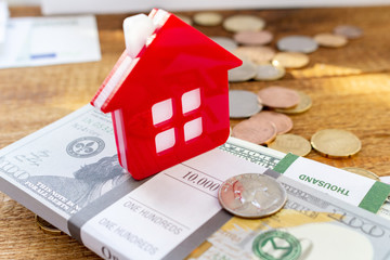 Red Home house on the banknotes and coins background euro dollar pile pack real estate concept expenses property buying mockup copy space close up background selective focus