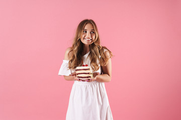 Canvas Print - Image of happy confused woman wearing white dress looking aside and holding piece of cake