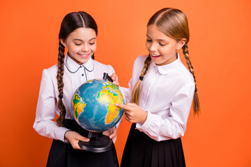 Portrait of two person nice attractive lovely winsome charming cute cheerful cheery curious pre-teen girls researching map route destination isolated over bright vivid shine orange background