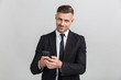 © Drobot Dean - Image of successful unshaven businessman in formal suit typing on cellphone and looking at camera