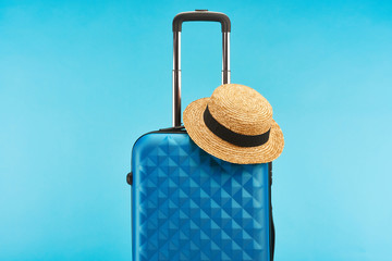 blue colorful travel bag with handle and straw hat isolated on blue