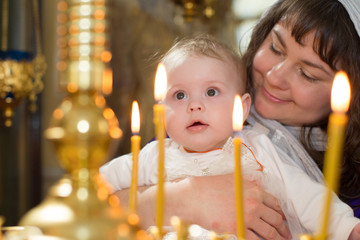 baptism of the child. the mother holds the child in the arms near the altar. the baby is in the chur