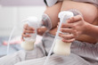 Young mother using electric breast pump pumping breast milk feeding for her baby.
