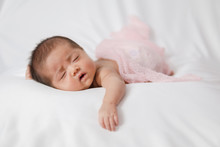 Adorable Asian Newborn Baby In Pink Wrap Sleeping On White Blanket Background.