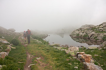 Wall Mural - some hikers walk along an old mule track near lake claus, in italy.
