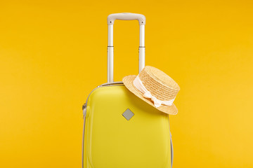 yellow colorful travel bag with straw hat isolated on yellow