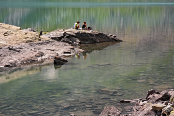 Wall Mural - a couple of tourists on the shores of an alpine lake, with green waters.