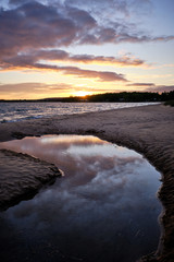 Wall Mural - a stream leads out to a lake during sunset with reflections in the water